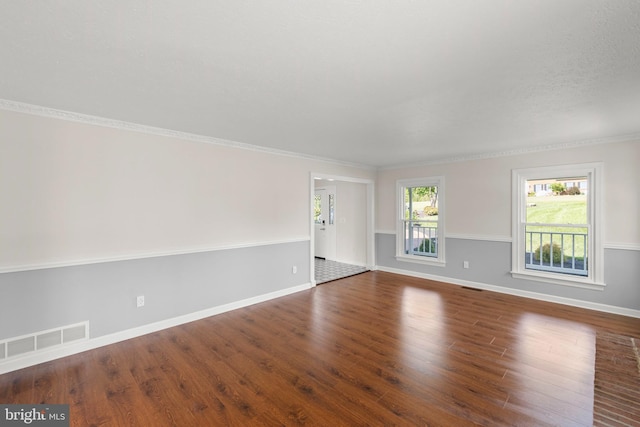 spare room with baseboards, ornamental molding, wood finished floors, and visible vents