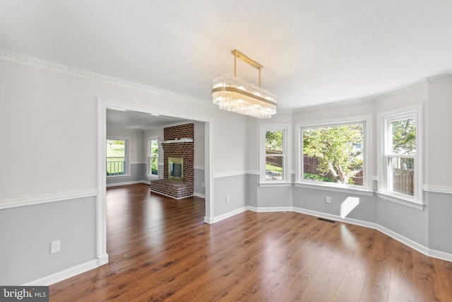 unfurnished dining area with visible vents, crown molding, baseboards, a notable chandelier, and hardwood / wood-style floors