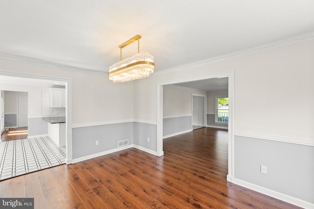 unfurnished dining area featuring ornamental molding, dark wood-type flooring, and a notable chandelier