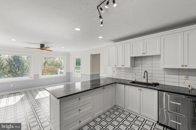 kitchen with white cabinets, a peninsula, recessed lighting, and a sink