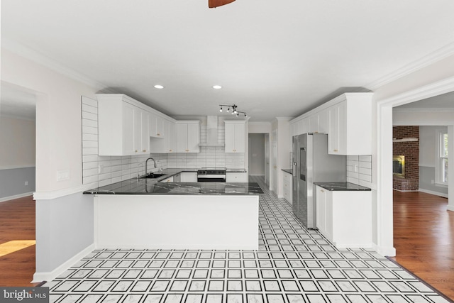 kitchen featuring range, crown molding, a sink, freestanding refrigerator, and a peninsula