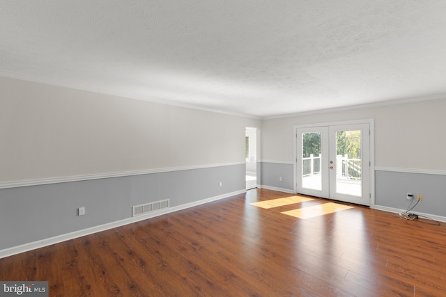 unfurnished room with a textured ceiling, visible vents, french doors, and wood finished floors