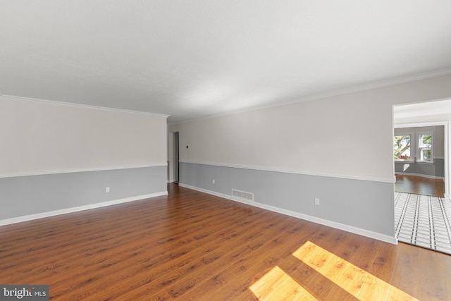 unfurnished room with ornamental molding, wood finished floors, and visible vents