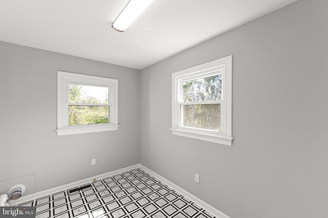 spare room with baseboards, tile patterned floors, and a wealth of natural light