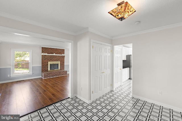 unfurnished living room with a brick fireplace, baseboards, ornamental molding, and tile patterned floors