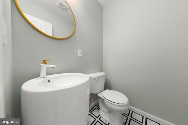 half bathroom with toilet, baseboards, and visible vents