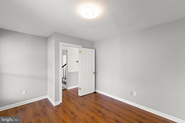 unfurnished bedroom featuring baseboards and dark wood finished floors