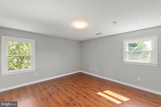 empty room with baseboards, wood finished floors, and a wealth of natural light