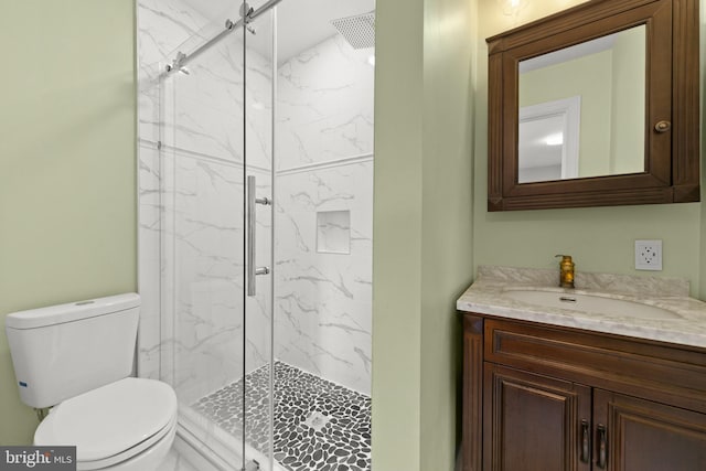 bathroom featuring toilet, a marble finish shower, and vanity