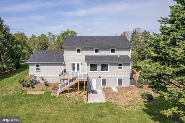 back of property featuring a lawn, a chimney, a patio area, and a wooden deck