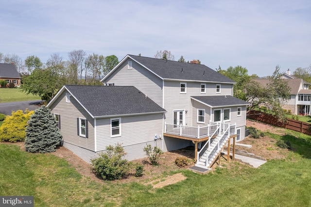 back of property with a lawn, a deck, a shingled roof, and stairs