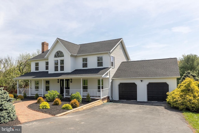 view of front facade with an attached garage, aphalt driveway, a chimney, and a porch