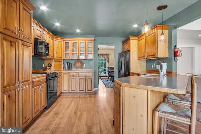 kitchen with a kitchen breakfast bar, a sink, black appliances, a peninsula, and light wood-style flooring