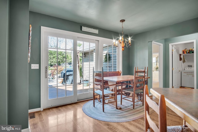 dining area with washer / clothes dryer, baseboards, a notable chandelier, and wood finished floors