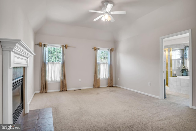 unfurnished living room featuring carpet, lofted ceiling, a wealth of natural light, and a fireplace