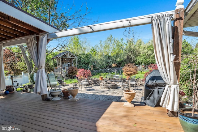 wooden deck featuring a fire pit, fence, and grilling area