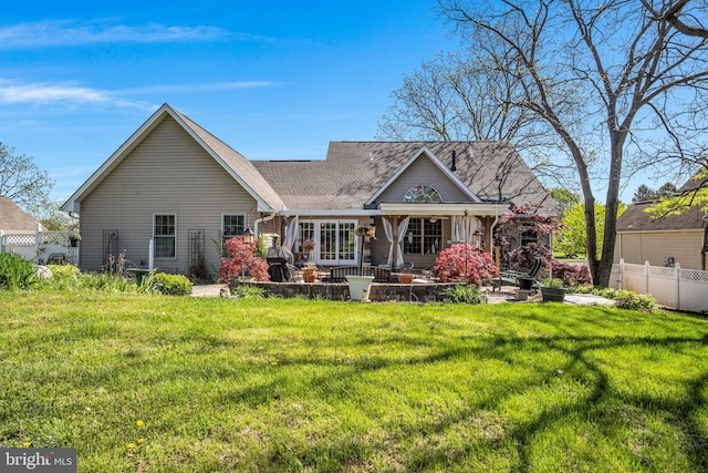 rear view of house featuring a lawn and fence