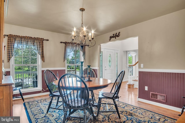 dining area with visible vents, wainscoting, wood finished floors, and a chandelier