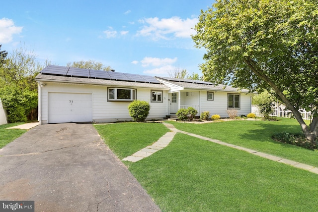 ranch-style house featuring an attached garage, a front lawn, aphalt driveway, and roof mounted solar panels