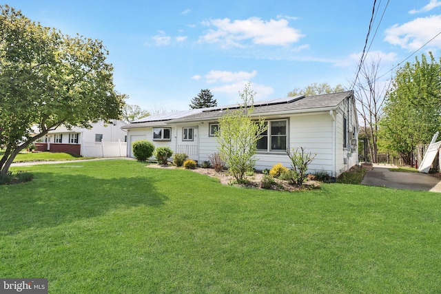 view of front of home featuring a front lawn, fence, and solar panels