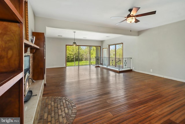 unfurnished living room featuring ceiling fan, dark wood finished floors, and baseboards