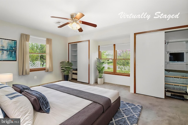 bedroom featuring carpet floors, a ceiling fan, two closets, and visible vents