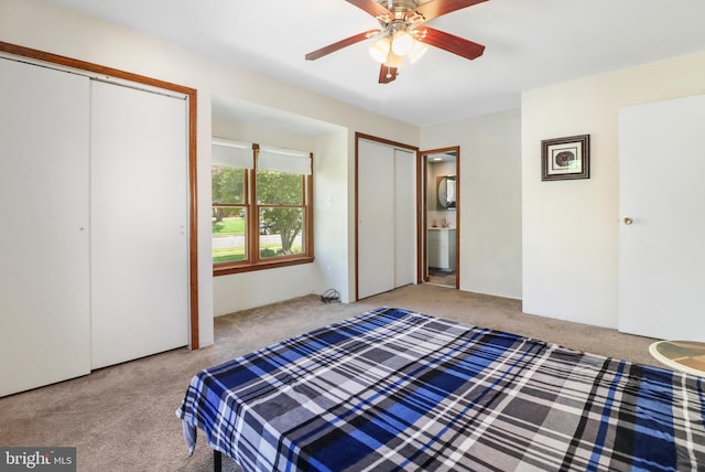 bedroom with a ceiling fan, ensuite bathroom, carpet, and two closets