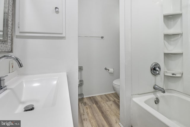 full bathroom with shower / bathtub combination, toilet, a sink, and wood finished floors