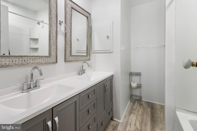 bathroom with double vanity, baseboards, a sink, and wood finished floors