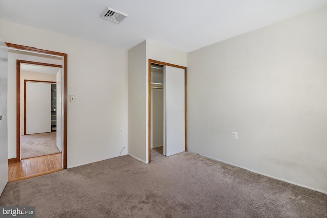 unfurnished bedroom with visible vents, carpet flooring, and a closet