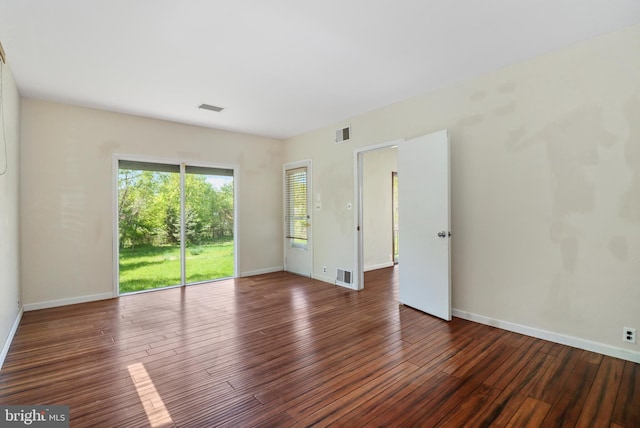 spare room with baseboards, visible vents, and wood finished floors