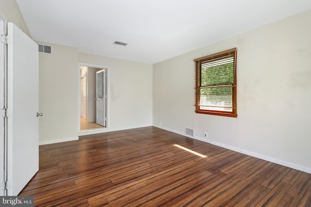 spare room with baseboards, wood finished floors, and visible vents