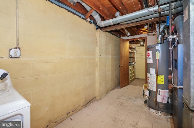 unfinished below grade area featuring concrete block wall, washer / dryer, and gas water heater