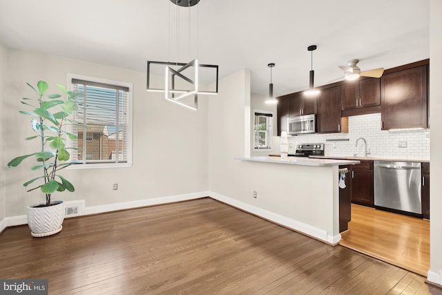 kitchen with light wood-style floors, light countertops, stainless steel appliances, and dark brown cabinets