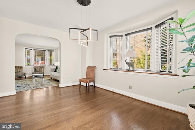 unfurnished room with baseboards, arched walkways, and wood finished floors