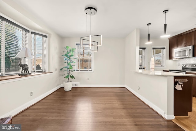 unfurnished dining area with baseboards, wood finished floors, and visible vents