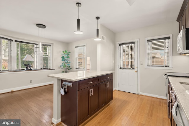 kitchen with hanging light fixtures, dark brown cabinetry, visible vents, and light wood-type flooring