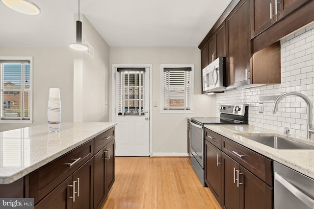 kitchen featuring dark brown cabinetry, appliances with stainless steel finishes, tasteful backsplash, light wood-type flooring, and a sink