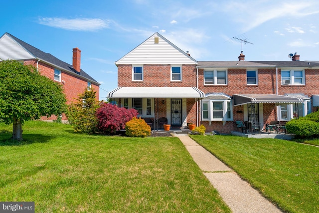 multi unit property with a porch, a front yard, and brick siding