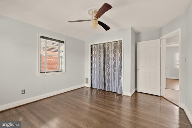 unfurnished bedroom with visible vents, a closet, wood finished floors, baseboards, and ceiling fan