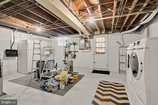 below grade area with separate washer and dryer, electric panel, and freestanding refrigerator