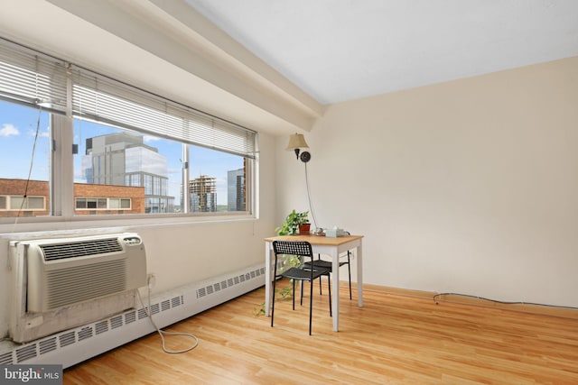 interior space with a view of city, a wall mounted air conditioner, a baseboard heating unit, and wood finished floors