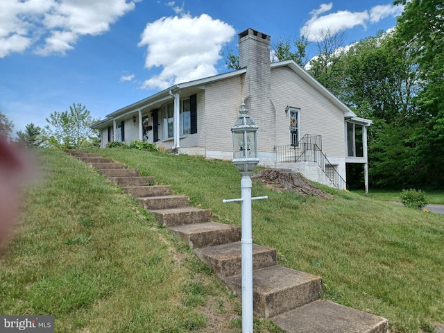exterior space featuring a chimney, stairs, and a front lawn