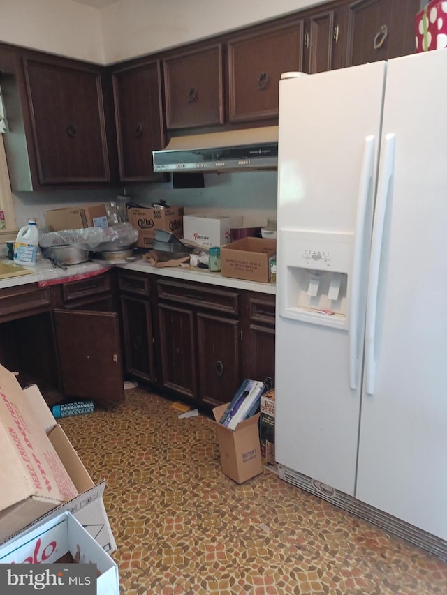 kitchen with light countertops, under cabinet range hood, white refrigerator with ice dispenser, and dark brown cabinetry