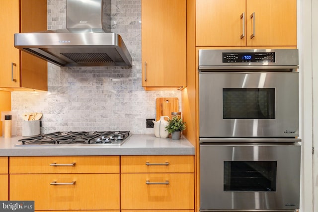 kitchen with light countertops, tasteful backsplash, wall chimney range hood, and stainless steel appliances
