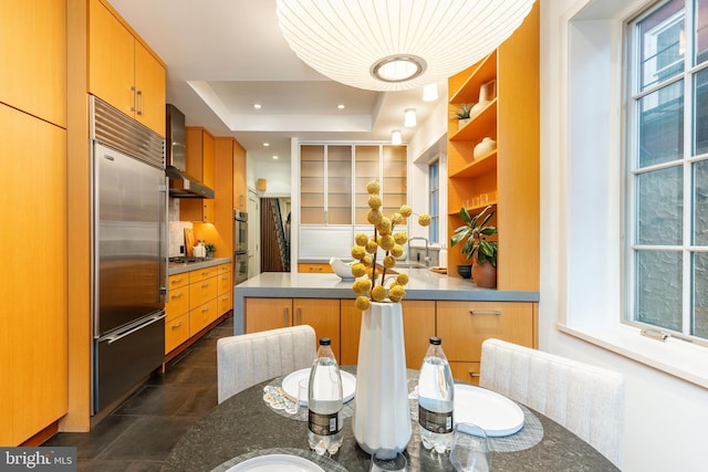 kitchen featuring stainless steel appliances, open shelves, a sink, a peninsula, and a tray ceiling