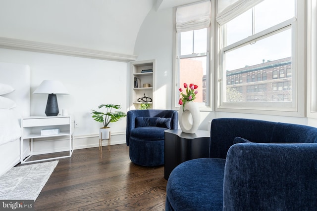 sitting room featuring dark wood-type flooring and built in shelves