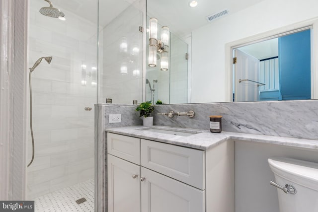 full bathroom with vanity, a shower stall, toilet, and visible vents