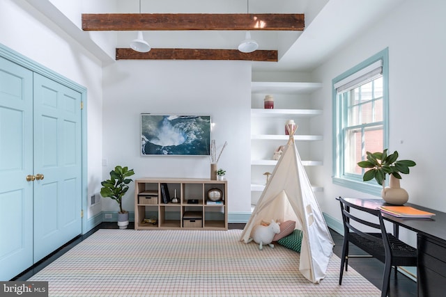 playroom featuring baseboards and beam ceiling