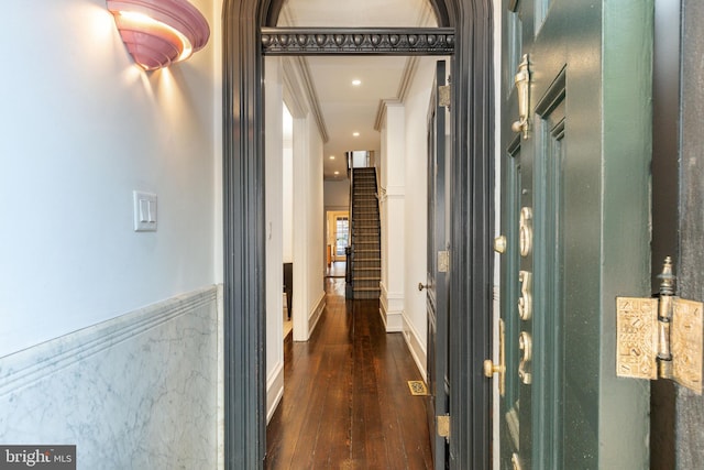 corridor featuring stairs, dark wood finished floors, ornamental molding, and a wainscoted wall